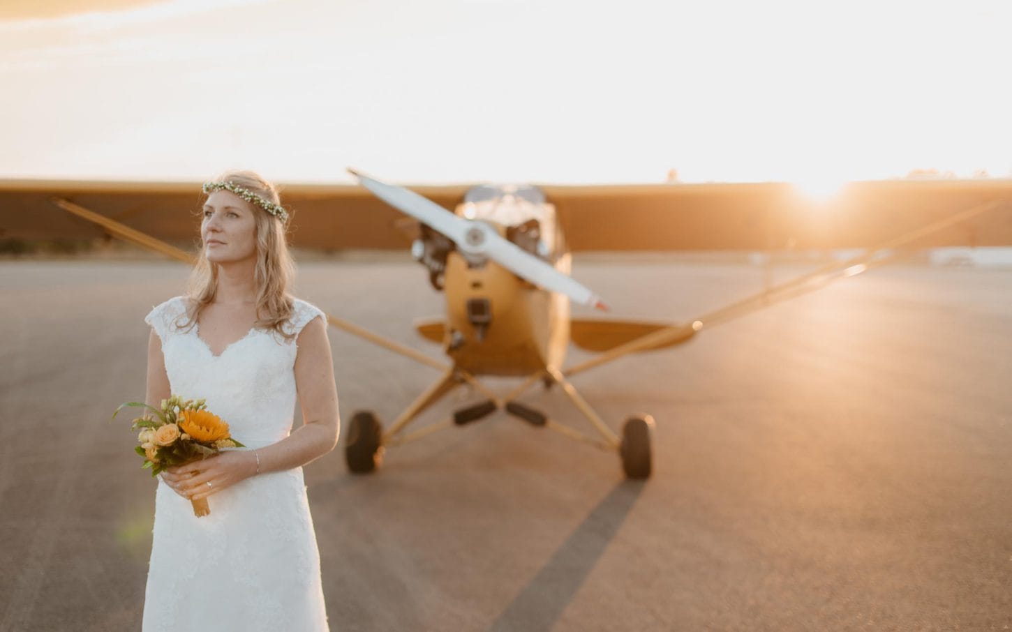 photo d'une mariée devant un avion biplace des années 40 lors d’une séance de couple day-after poétique & romantique sur le thème du voyage à l’aérodrome d’Ancenis par Geoffrey Arnoldy photographe