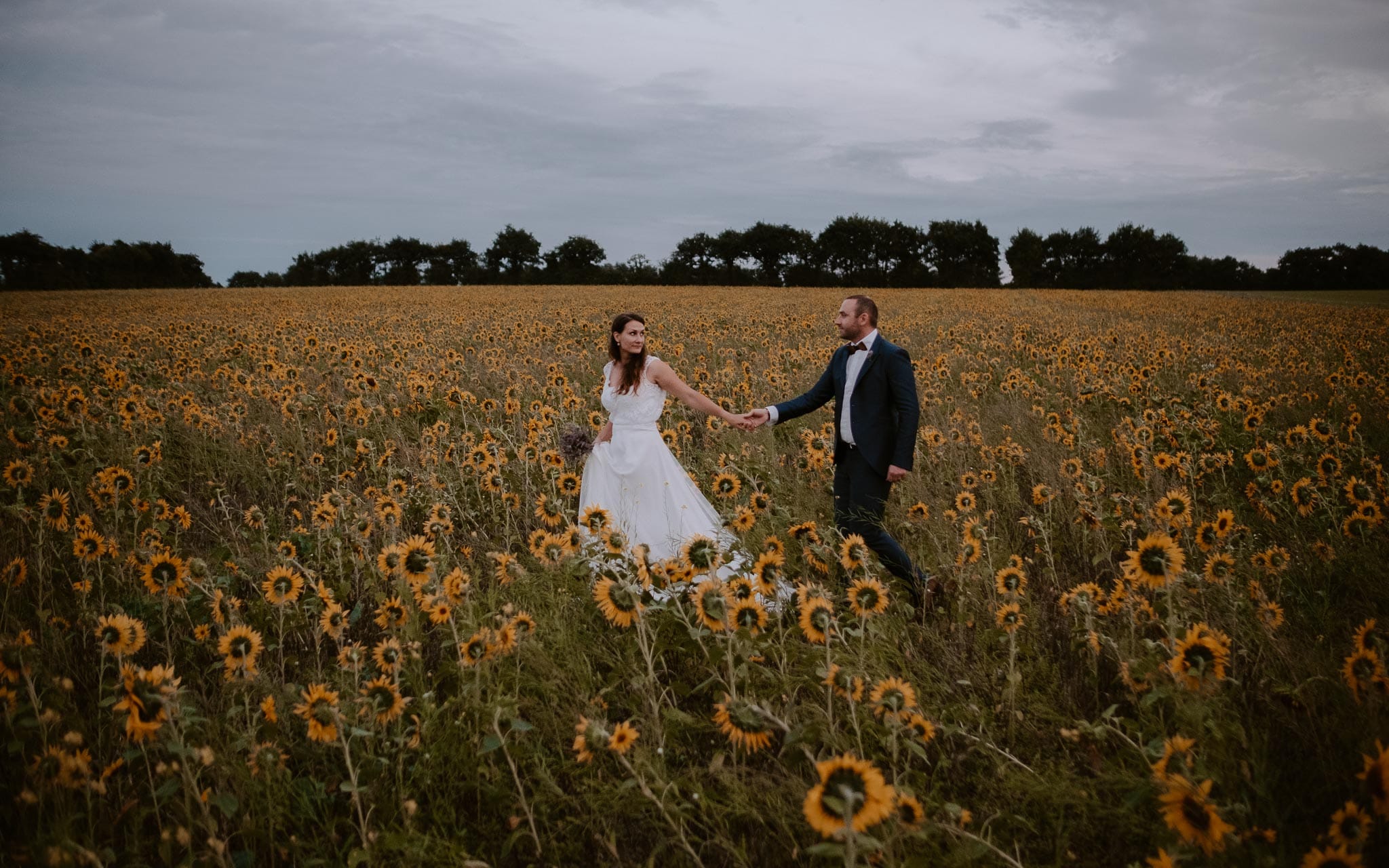 Séance couple après mariage naturelle et romantique dans un champ de tournesols en vendée par Geoffrey Arnoldy photographe