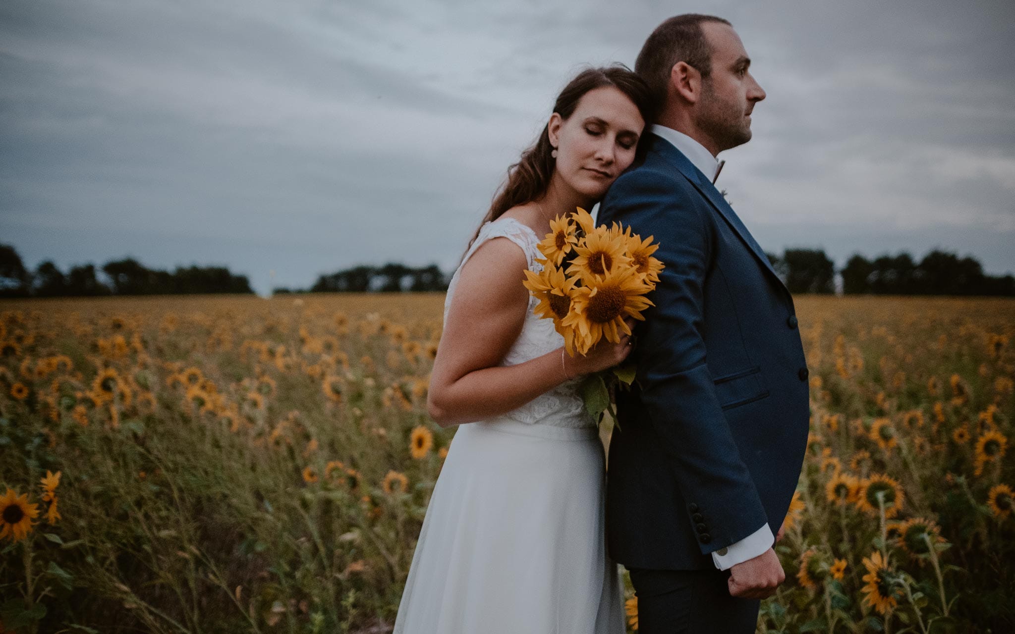 Séance couple après mariage naturelle et romantique dans un champ de tournesols en vendée par Geoffrey Arnoldy photographe