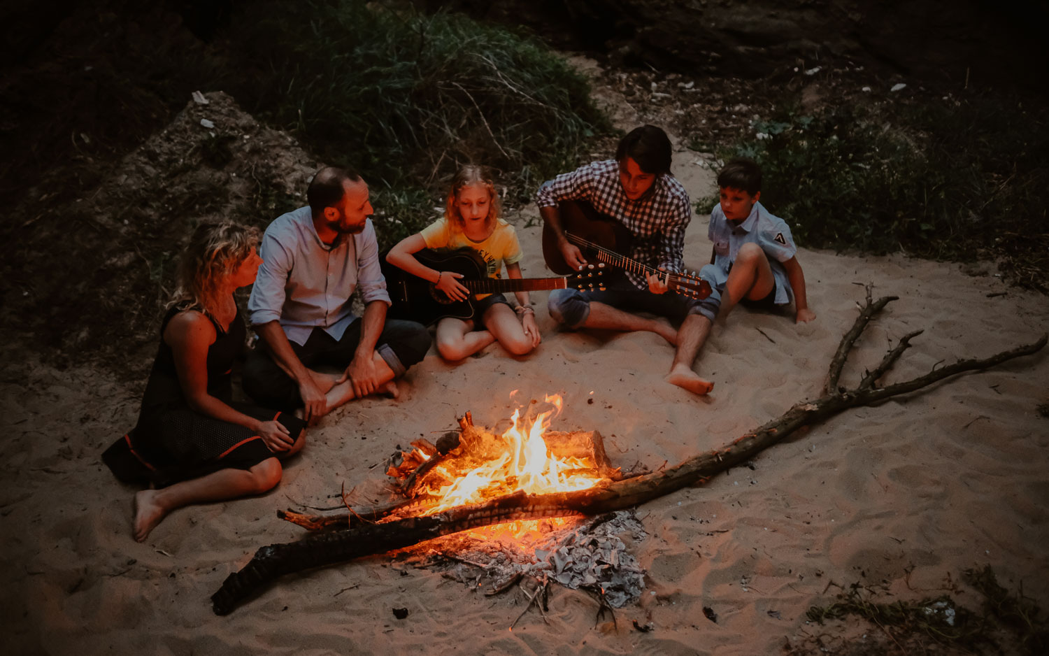 Séance photo de famille parents enfant en extérieur jouant de la musique autour d’un feu en été à Pornic par Geoffrey Arnoldy photographe