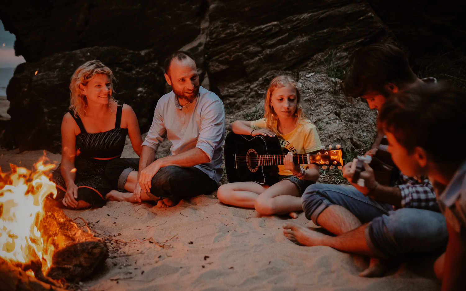Séance photo de famille parents enfant en extérieur jouant de la musique autour d’un feu en été à Pornic par Geoffrey Arnoldy photographe