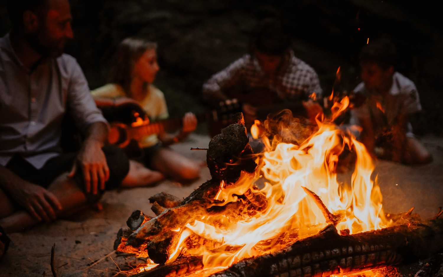 Séance photo de famille parents enfant en extérieur jouant de la musique autour d’un feu en été à Pornic par Geoffrey Arnoldy photographe