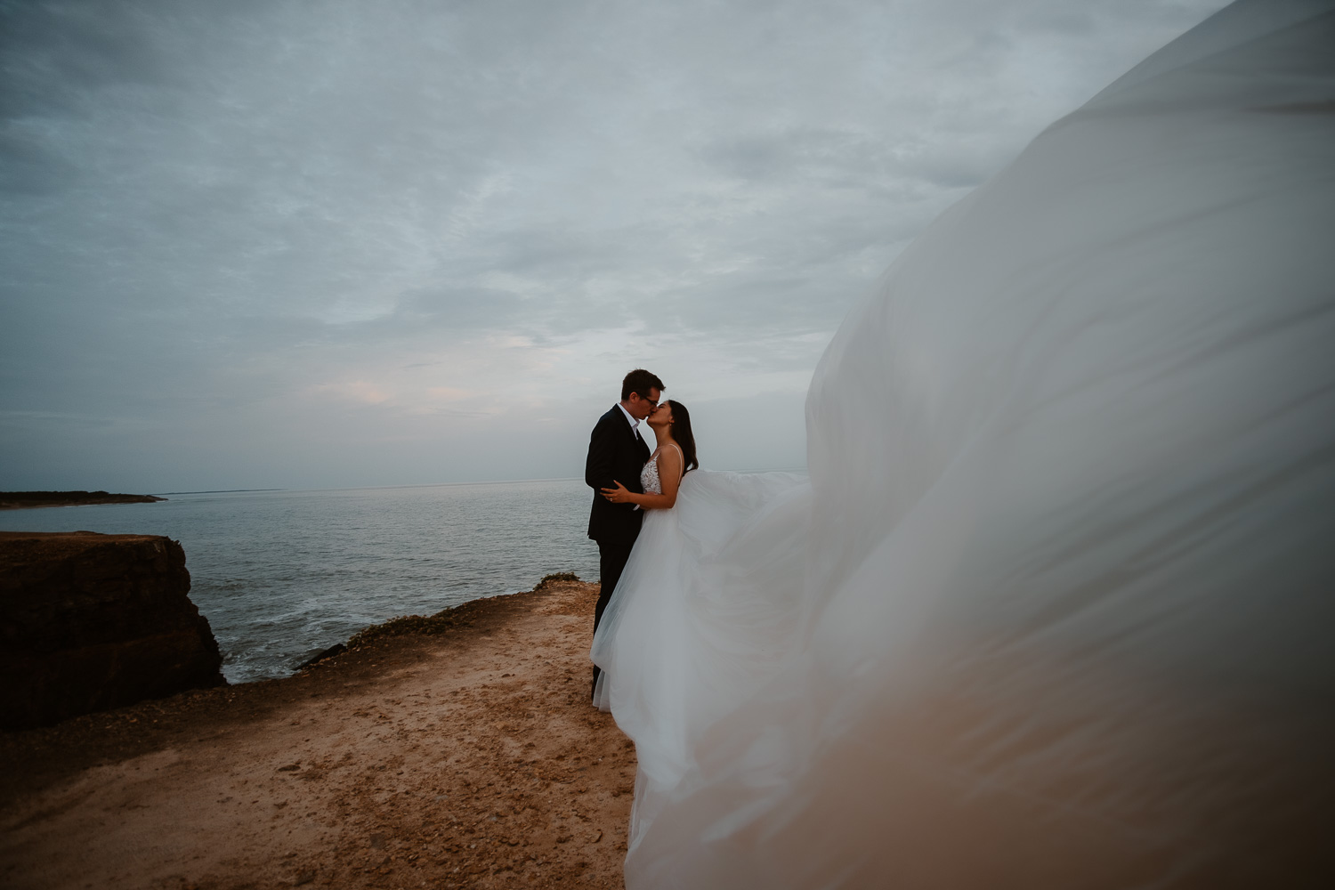 Photographie poétique au bord de l'océan d’un couple de mariés