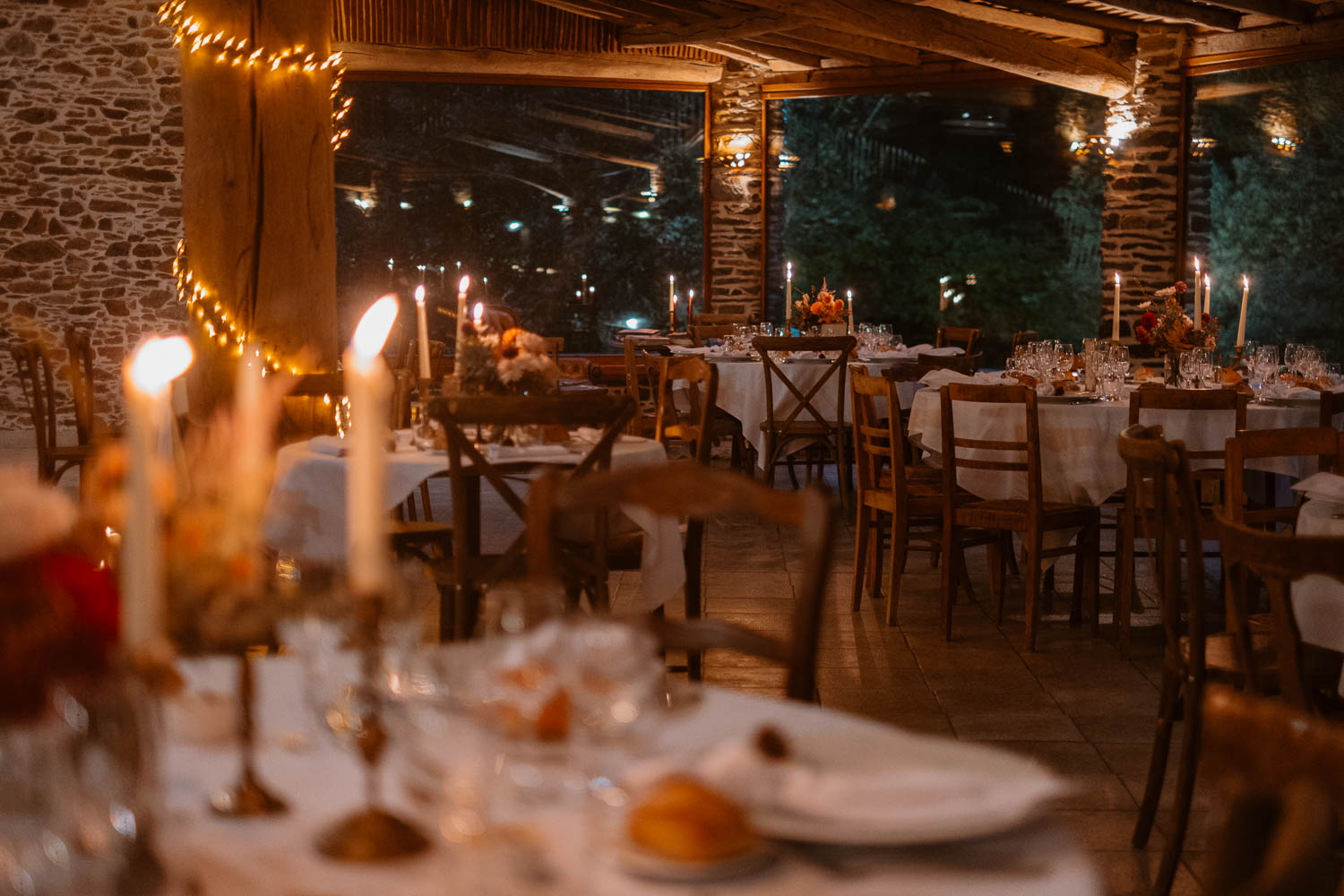 Photographie d'une salle de mariage en automne à la tombée de la nuit à la lumière des bougies