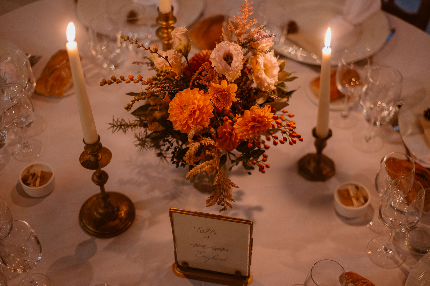 Photographie des tables d'un mariage en automne à la tombée de la nuit à la lumière des bougies